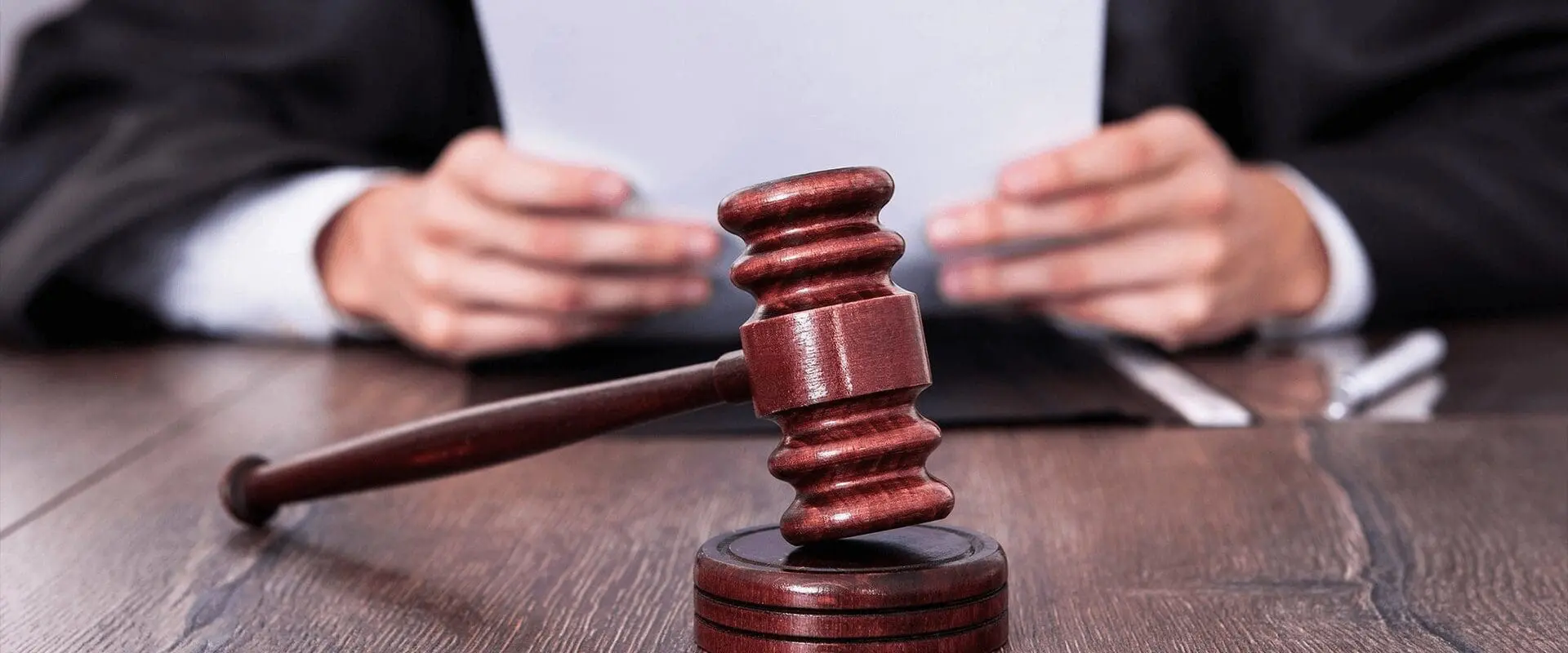 A judge 's gavel sitting on top of a wooden table.