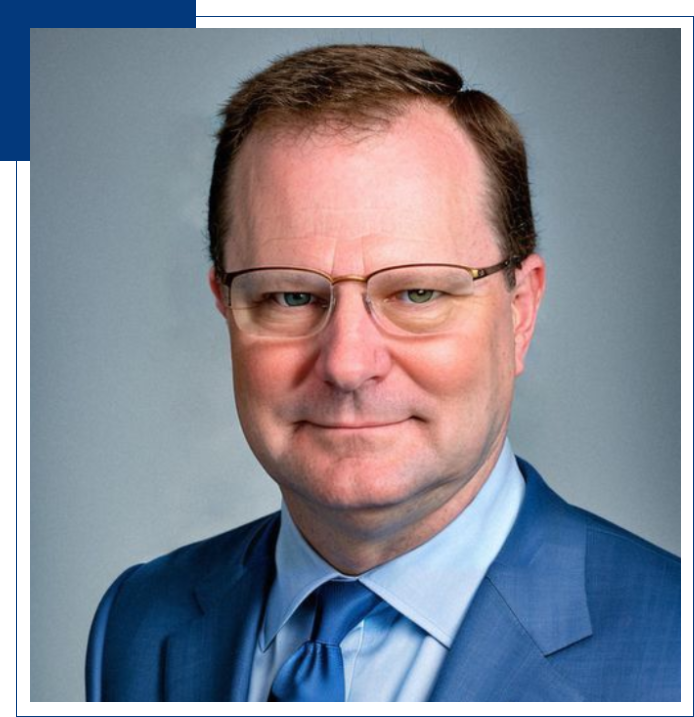 Headshot of man in blue suit and glasses.